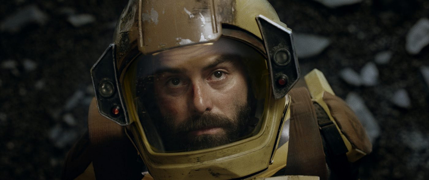 Close of a person wearing a spacesuit staring into the distance