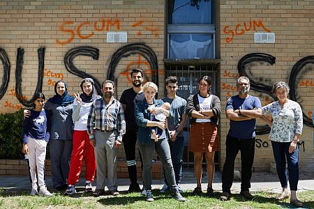 The residents of Arcadia Towers standing in front of graffitied building